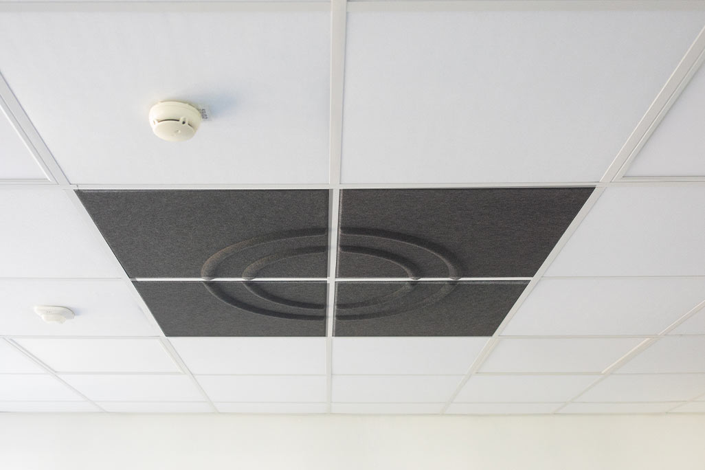 Section of a standard grid ceiling with inlaid soni COMFORT SD acoustic absorbers in white and soni COLOR Design in anthracite.