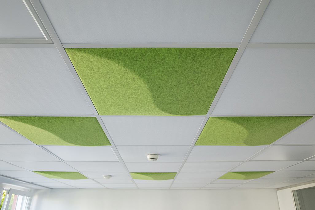 Section of a standard grid ceiling with inlaid soni COMFORT SD acoustic absorbers in white and soni COLOR Design in green.