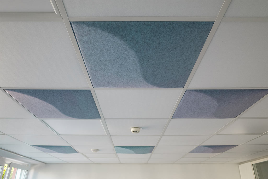 Section of a standard grid ceiling with inlaid soni COMFORT SD acoustic absorbers in white and soni COLOR Design in blue.