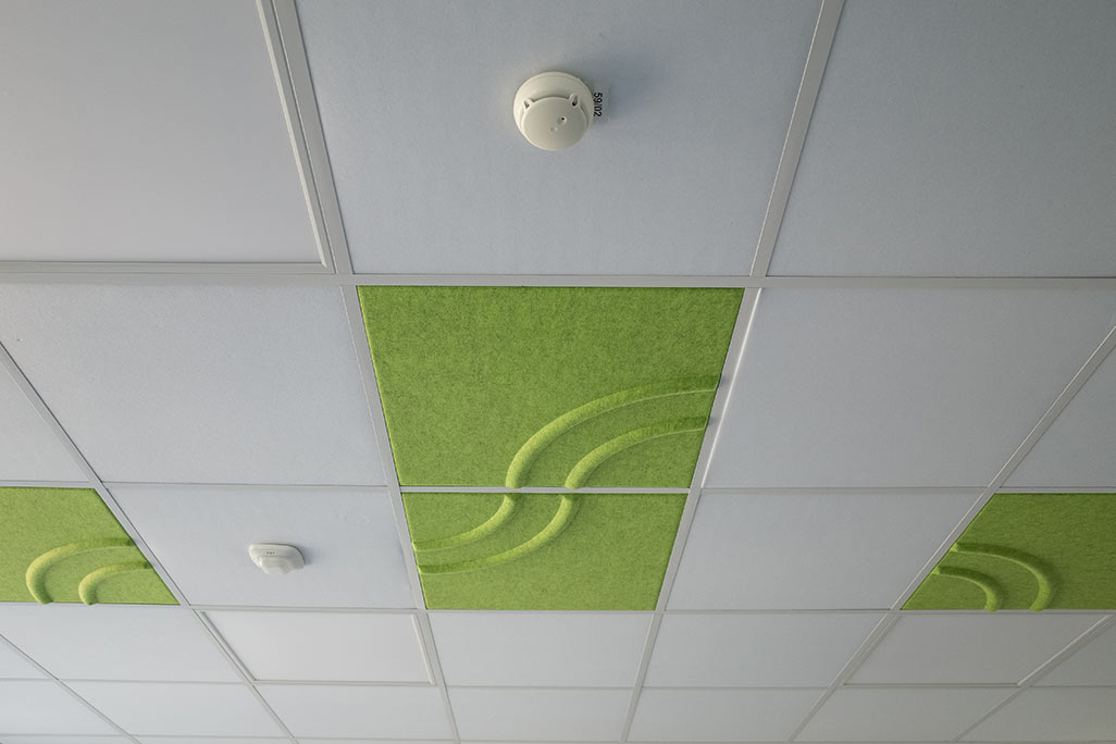 Section of a standard grid ceiling with inlaid soni COMFORT SD acoustic absorbers in white and soni COLOR Design in green.