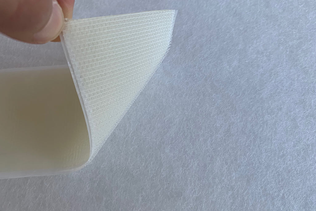 Sample of a white PES-VLieses, to which a soni KLettband was attached