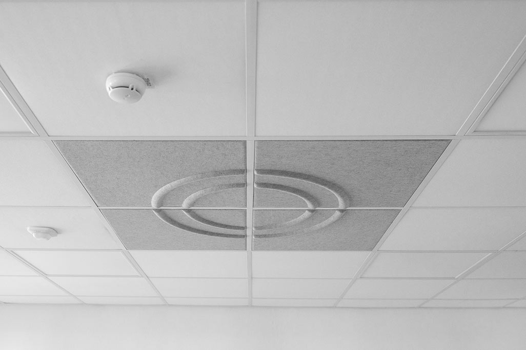 Section of a standard grid ceiling with inlaid soni COMFORT SD acoustic absorbers in white and soni COLOR Design in light gray.