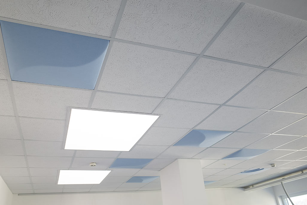 Section of a standard grid ceiling with inlaid soni COMFORT SD acoustic absorbers in white and soni COLOR Design in blue.