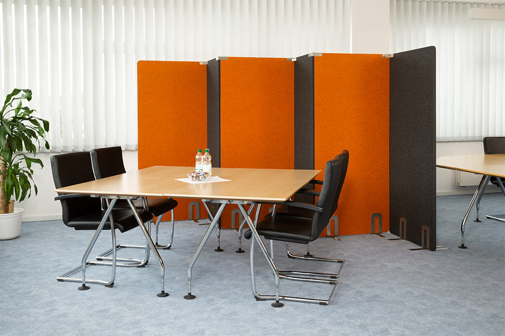 Meeting room with a table and 4 chairs, behind it 5 soniflex partitions next to each other as a separate wall in the room