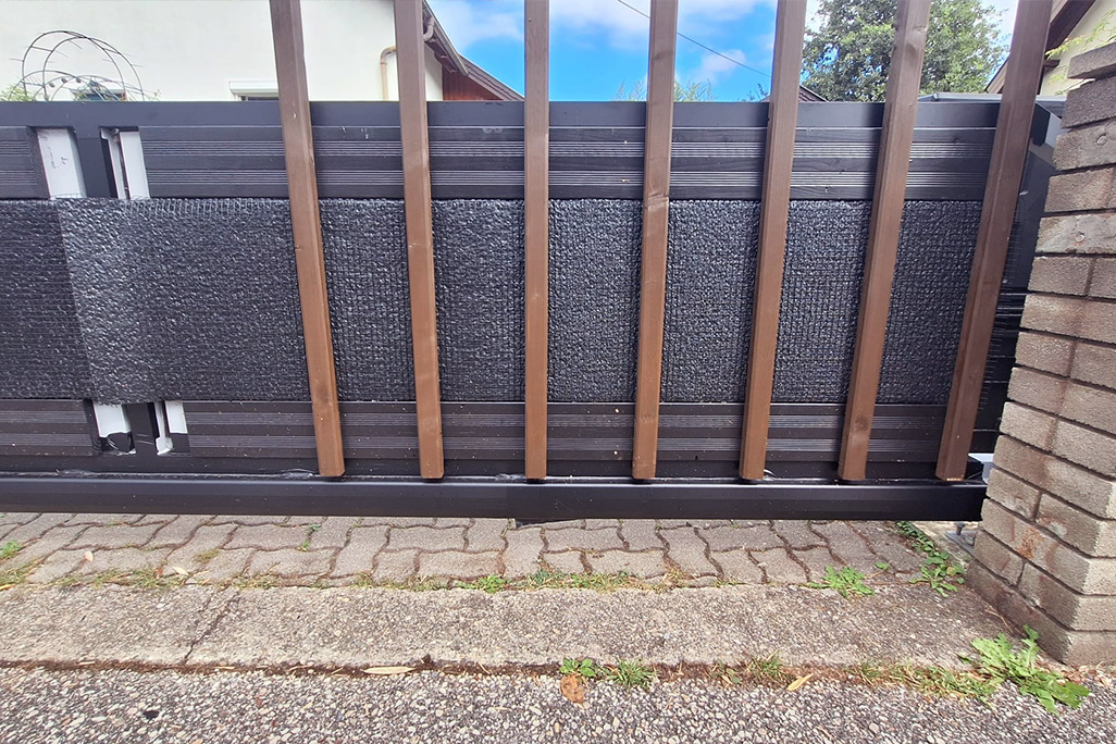 Zufahrtstor mit Schallschutzplatten hinter Holzleisten