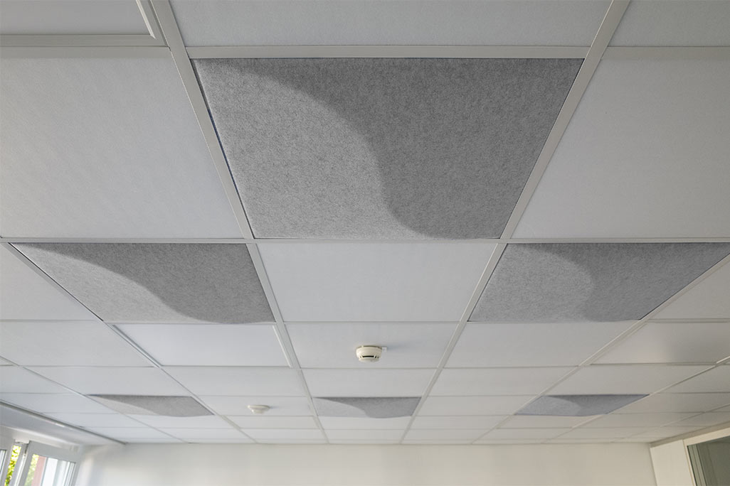 Section of a standard grid ceiling with inlaid soni COMFORT SD acoustic absorbers in white and soni COLOR Design in light gray.