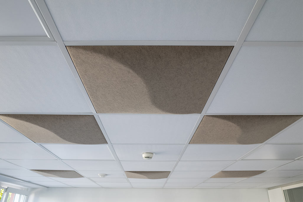 Section of a standard grid ceiling with inlaid soni COMFORT SD acoustic absorbers in white and soni COLOR Design in beige.