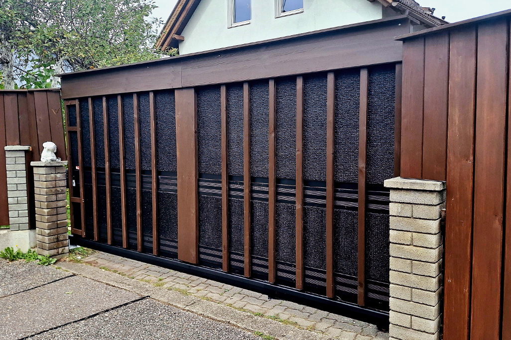 Zufahrtstor mit Schallschutzplatten hinter Holzleisten