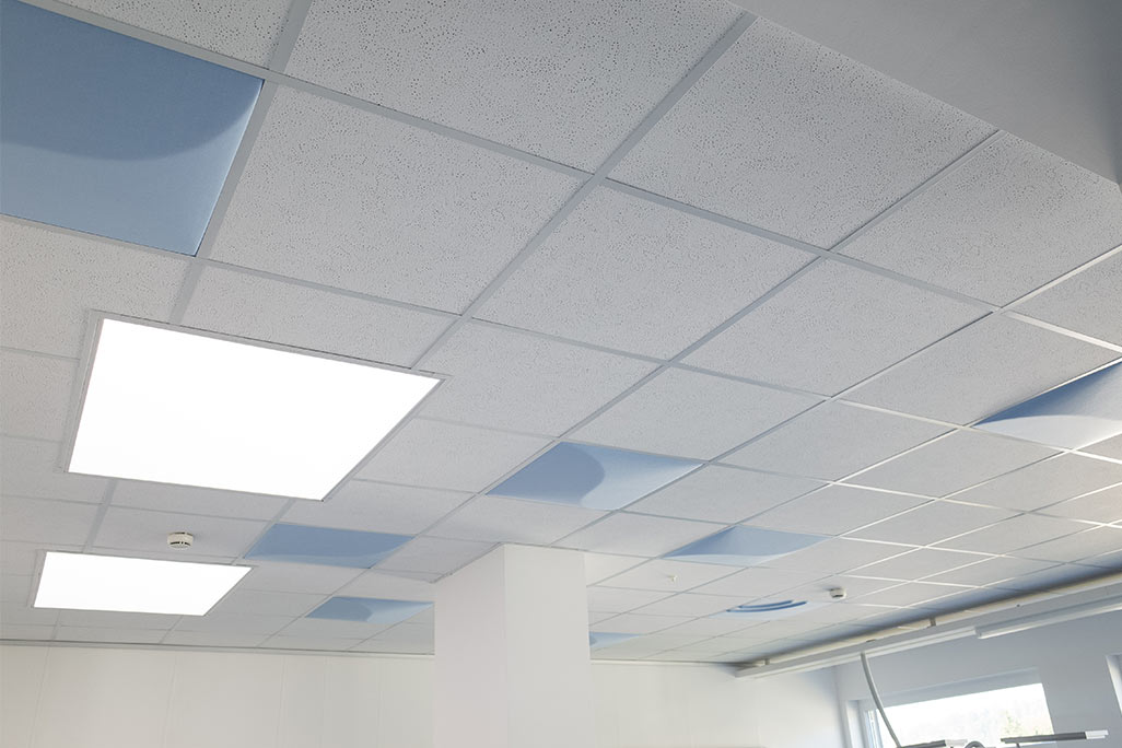 Section of a standard grid ceiling with inlaid soni COMFORT SD acoustic absorbers in white and soni COLOR Design in blue.