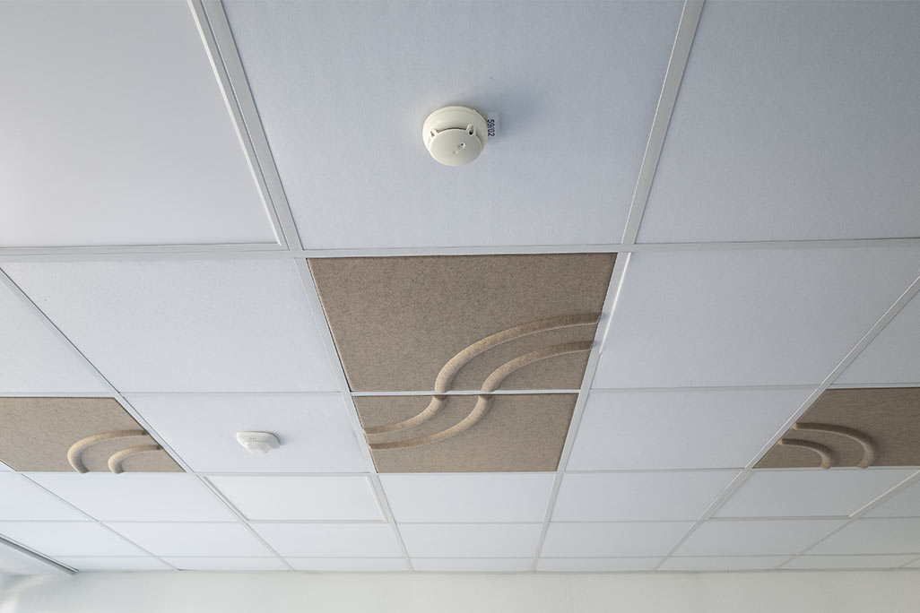 Section of a standard grid ceiling with inlaid soni COMFORT SD acoustic absorbers in white and soni COLOR Design in beige.