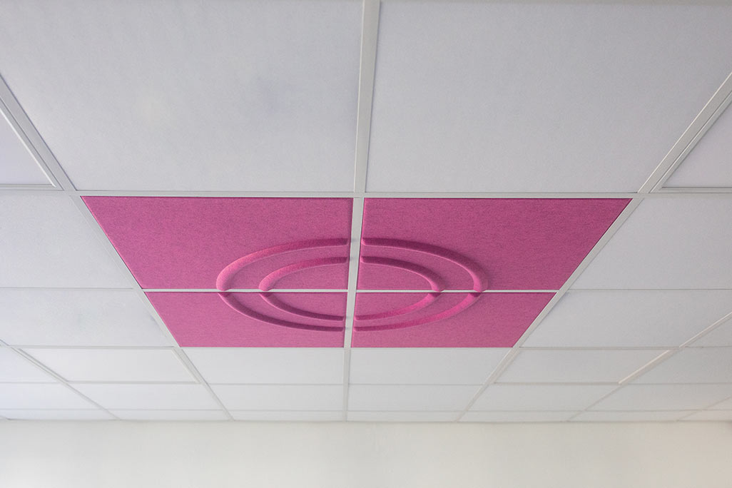 Section of a standard grid ceiling with inlaid soni COMFORT SD acoustic absorbers in white and soni COLOR Design in pink.