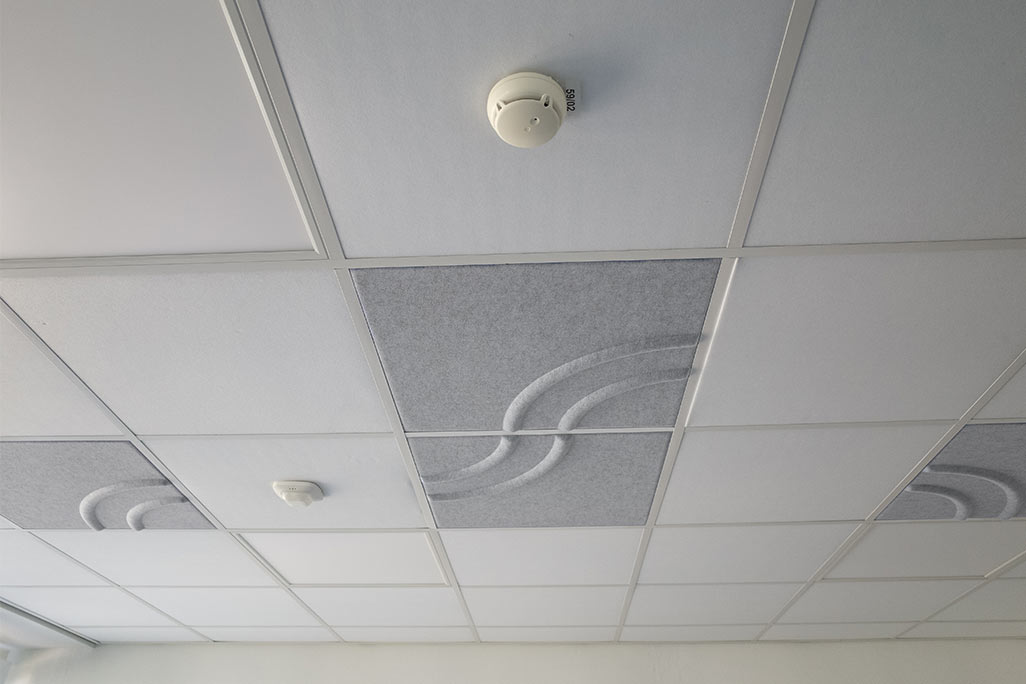Section of a standard grid ceiling with inlaid soni COMFORT SD acoustic absorbers in white and soni COLOR Design in light gray.