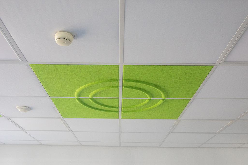 Section of a standard grid ceiling with inlaid soni COMFORT SD acoustic absorbers in white and soni COLOR Design in green.