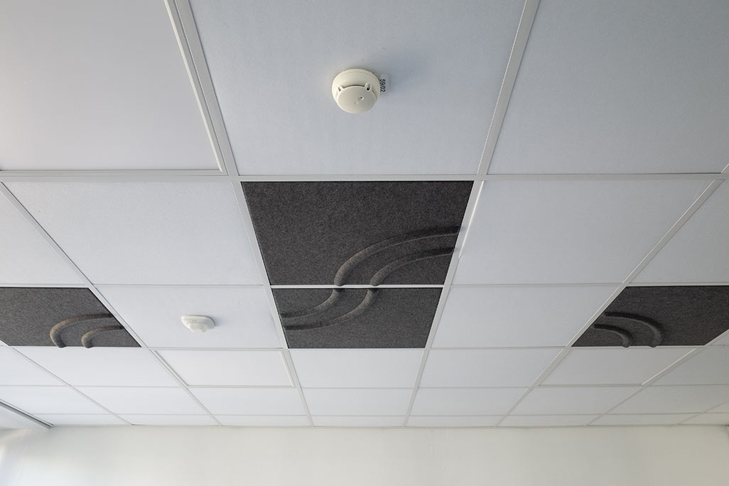 Section of a standard grid ceiling with inlaid soni COMFORT SD acoustic absorbers in white and soni COLOR Design in anthracite.