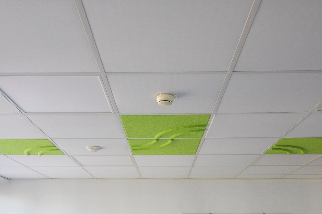 Section of a standard grid ceiling with inlaid soni COMFORT SD acoustic absorbers in white and soni COLOR Design in green.