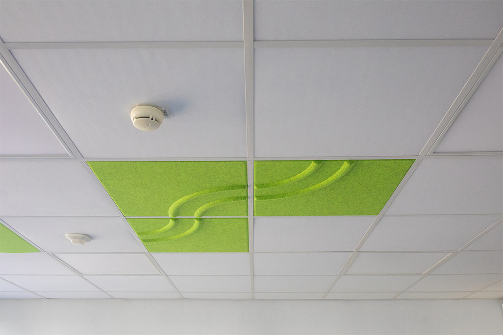 Ausschnitt einer handelsüblichen Rasterdecke mit eingelegten Akustikabsorbern soni COMFORT SD in Weiß und soni COLOR Design in Grün.